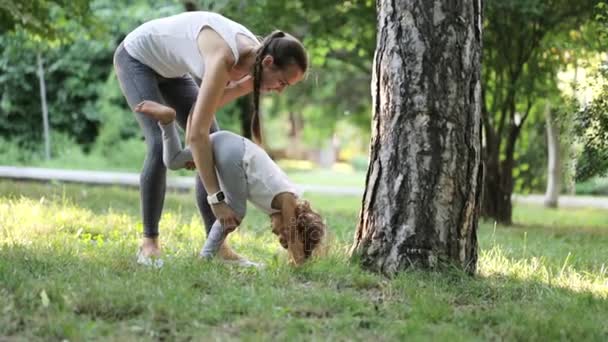 Joven madre deportista entrenando a su hija pequeña en el verde parque de verano — Vídeos de Stock