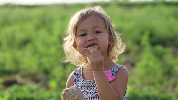 Retrato de una niña comiendo pan casero en el campo de la granja ecológica — Vídeos de Stock