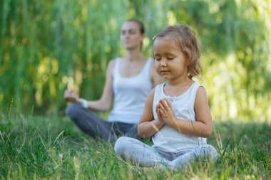 Genç anne ve sevimli küçük kız meditasyon lotus birlikte poz