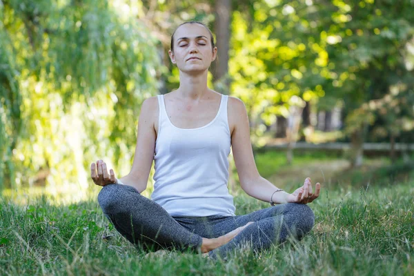 Genç sportif çekici kadın meditasyon lotus poz Park'ta yeşil yaz