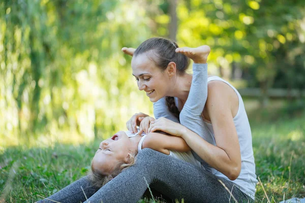 Anne ve küçük kızı eğleniyor yeşil yaz çimen çayır üzerinde
