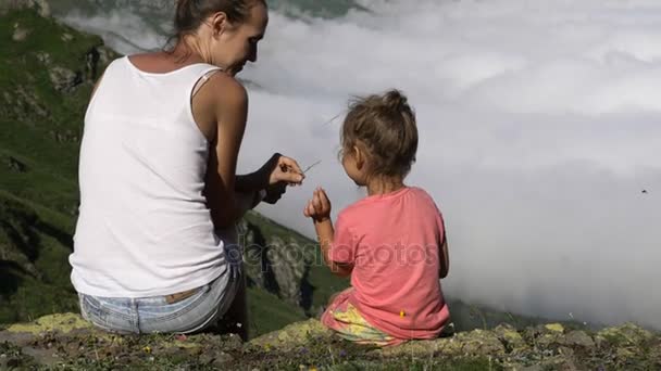 Jovem mulher com pouco bonito filha sentado no topo da montanha . — Vídeo de Stock