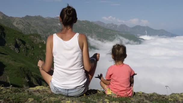 Mujer joven con pequeña hija linda meditando en la cima de la montaña . — Vídeos de Stock