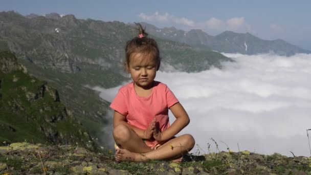 Schattig meisje mediteren op de top van berg — Stockvideo