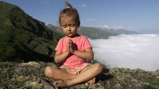 Pequena menina bonito meditando no topo da montanha — Vídeo de Stock