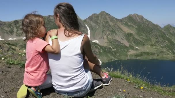 Mujer joven con una linda hija sentada en la cima de la montaña . — Vídeos de Stock