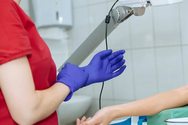 Przytnij obraz pielęgniarki zakładanie niebieskie Rękawice medyczne do pobierania próbek krwi — Zdjęcie stockowe