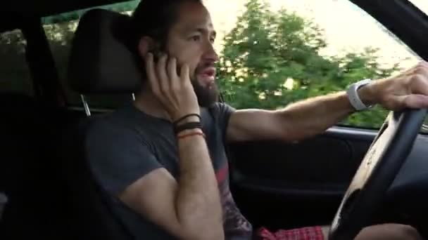 Человек за рулем автомобиля в сельской местности и с помощью устройства громкой связи, чтобы сделать звонок — стоковое видео