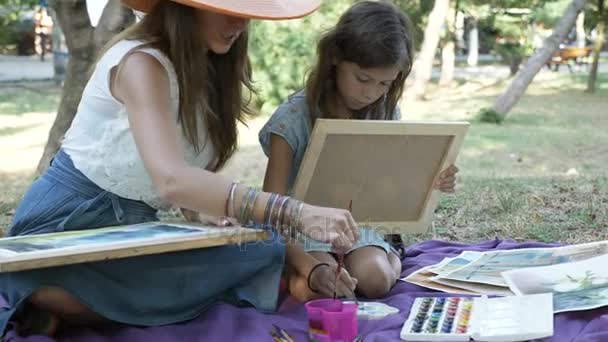 Woman with daughter drawing by watercolor paints at the park — Stock Video