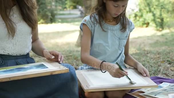 Женщина с дочерью рисует акварелью в парке — стоковое видео