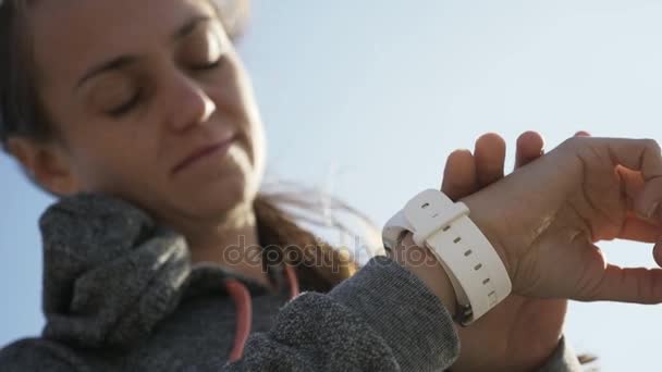 Zbliżenie kobieta za pomocą inteligentnego sport uruchomiona zegarek na plaży — Wideo stockowe