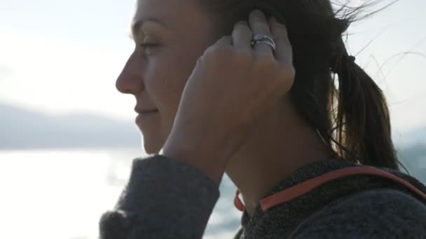 Nahaufnahme Porträt einer Fitness-Frau, die sich einen drahtlosen In-Ear-Kopfhörer aufsetzt. — Stockvideo