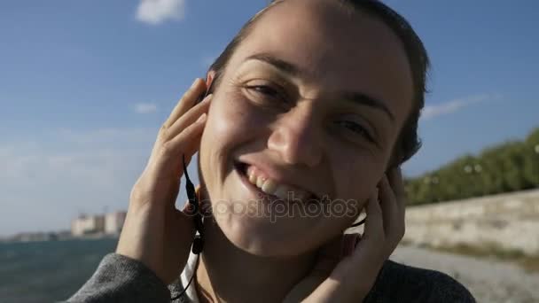 Joven mujer alegre divertida escuchando música en auriculares, sonrisa, risa y danza — Vídeos de Stock