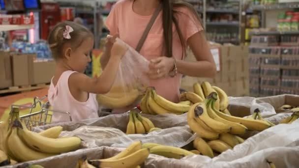 Närbild av mor och lilla dotter att välja frukt i snabbköpet. — Stockvideo