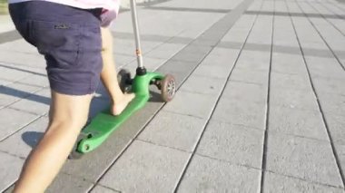 Mutlu sevimli küçük kız sürme tekme scooter güneşli yaz günü Park