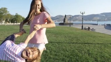 Küçük şirin kızı güneşli bir günde döne döne parkta genç mutlu anne