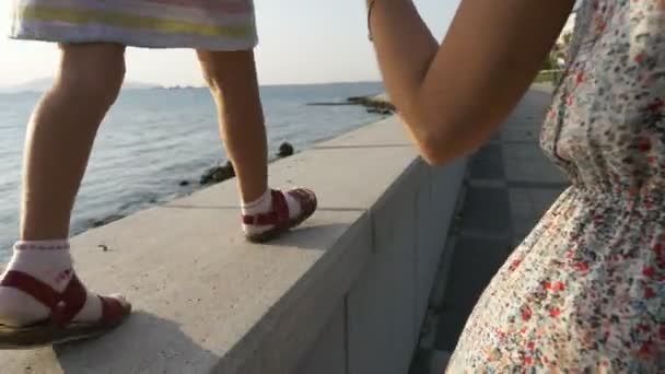 Mujer va de la mano con una niña hermosa por la mañana en la ciudad junto al mar — Vídeo de stock