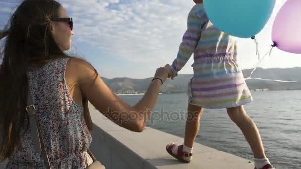 女人的手与运行一个小的美丽女孩上午在市海滨 — 图库视频影像