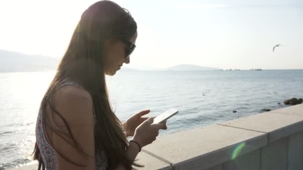 Junge Frau mit Smartphone an der Strandpromenade in der Stadt, Steadicam-Aufnahme — Stockvideo