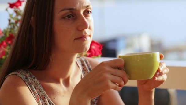 Jovem mulher bonita senta-se em um café contemplando belas vistas da baía do mar . — Vídeo de Stock