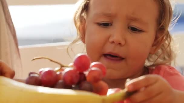 Vídeo divertido de la niña linda jugando con frutas en el balcón — Vídeo de stock