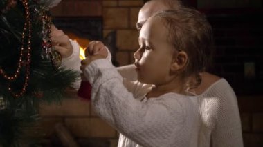 Genç anne küçük sevimli kızıyla birlikte Noel ağacı süsleme