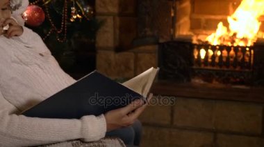 Şömine ve Noel ağacı yanında küçük kızı okuma kitabı ile anne