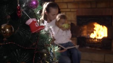 Arka planda şömine yakın aile okuma kitabı ile Noel ağacı