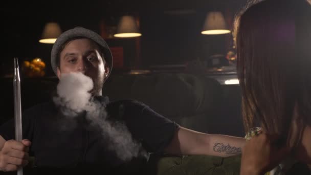 Kluk s dívkou sedí na pohovce v kavárně a kouření vodní dýmky — Stock video