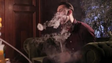 Nargile ve yapar halkalar duman sigara yakışıklı genç adam.