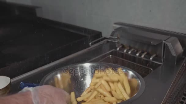 Chef mixing and salting french fries in steel bowl, close-up slow motion. — Stock Video