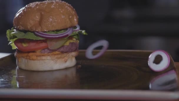 Círculos de cebolla fresca cayendo en la hamburguesa, cámara lenta, concepto de comida chatarra . — Vídeos de Stock