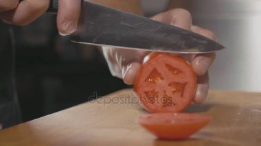 Closeup Şef kesme dilim domates ahşap kesme tahtası üzerinde eller