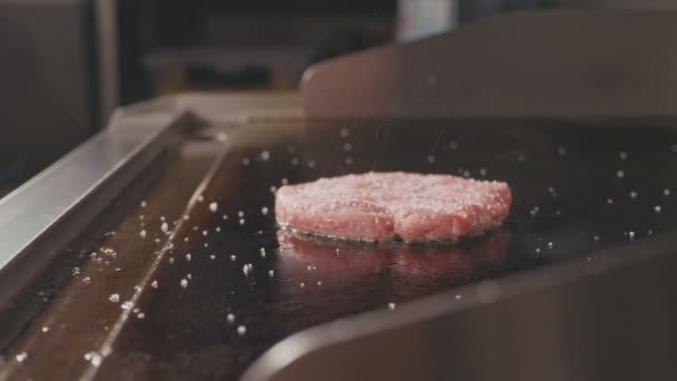 Nära upp skott av rå nötkött kotlett till burger stekning på elektriska kommersiella grill. — Stockvideo