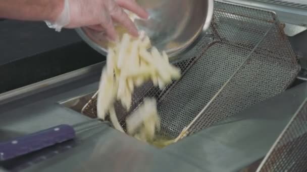 Chefs manos vertiendo una papa a una freidora para cocinar papas fritas — Vídeo de stock