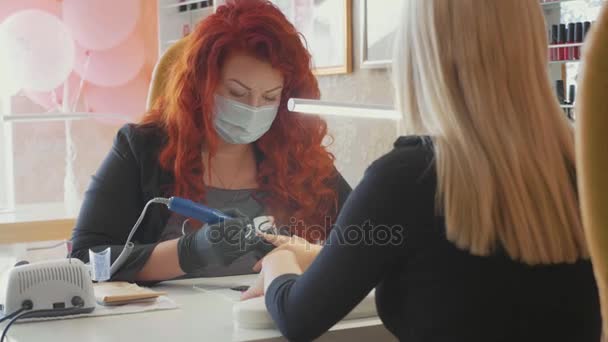 Manicurist is applying electric nail file drill to manicure on female fingers. — Stock Video