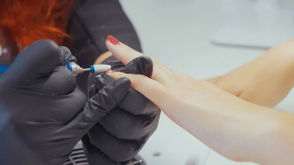 Close-up of manicurist removing the old gel polish using elecrtric nail file. — Stock Photo, Image