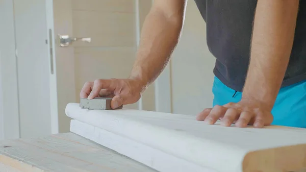 Крупный план мужских рук, полирующих деревянные ступеньки наждачной бумагой — стоковое фото