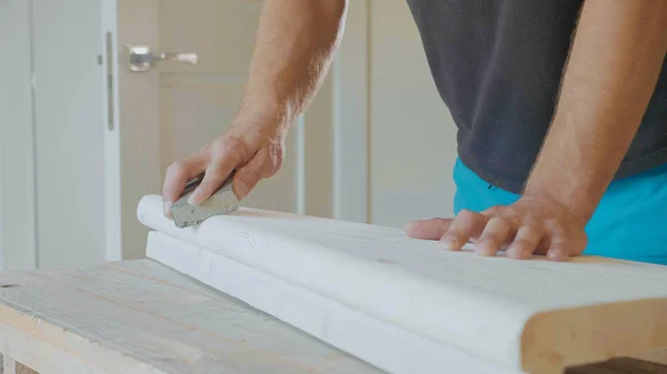 Крупный план мужских рук, полирующих деревянные ступеньки наждачной бумагой — стоковое фото