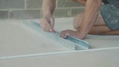Yeni inşa edilen evde yüklemek için bir alçıpan levha işaretleme işçisi.