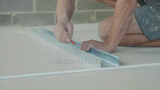 Εργαζόμενος σήμανση ένα φύλλο του ξηρού τοίχου για την εγκατάσταση στο νεόκτιστο σπίτι. — Αρχείο Βίντεο