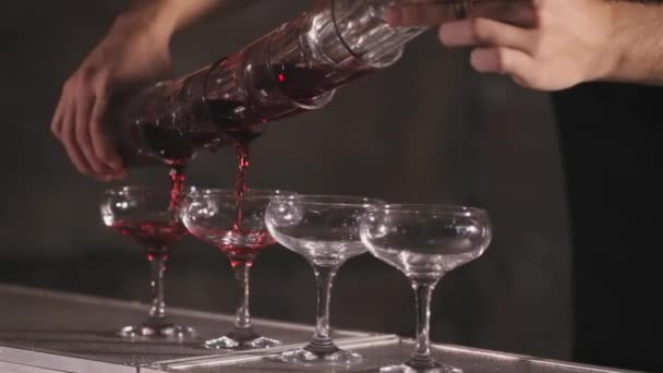 Barmann gießt aus vier Gläsern gleichzeitig Alkohol in vier Essiggläser — Stockvideo