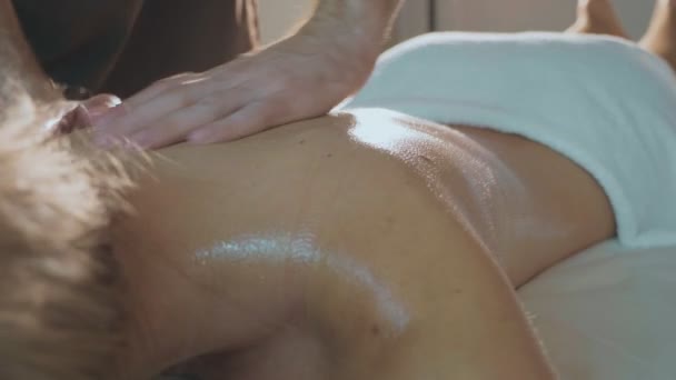 Ung vacker kvinna ligger på soffan i spa och åtnjuter ryggmassage, närbild — Stockvideo