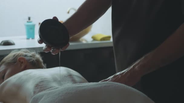 Massageterapeut hälla olja för massage på kvinnliga baksidan — Stockvideo