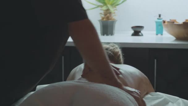 Ung vacker kvinna ligger på soffan i spa och åtnjuter ryggmassage — Stockvideo