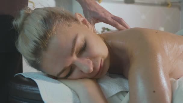 Porträt einer jungen Frau, die im luxuriösen Wellness-Salon auf der Couch liegt und Rückenmassage erhält — Stockvideo