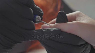 Manikürcü kadın parmaklarına manikür yapmak için elektrikli tırnak matkabı uyguluyor..