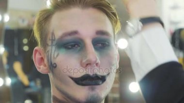 Erkek modeller yüzünde Cadılar Bayramı makyaj uygulamak sanatçı.