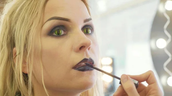 Genç güzel kadın yüzünde Cadılar Bayramı makyaj uygulayarak işlemi