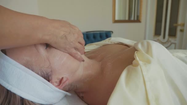 Joven hermosa mujer recibiendo una máscara facial cosmética en el primer plano del salón de spa de lujo — Vídeo de stock